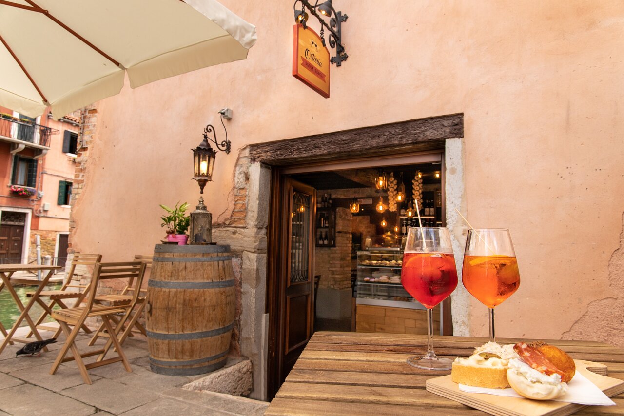 L’ingresso dell’Ostaria con tavoli all’aperto e spritz