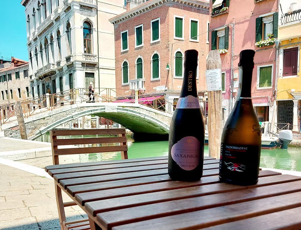 Due bottiglie di bollicine su un tavolo davanti al ponte sul canale